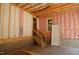 Interior view of an unfinished basement, with exposed insulation, stairway, and a white door at 4109 Stonewall Dr, Raleigh, NC 27604
