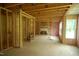 Unfinished living room with exposed framing, beams, insulation, and a window to the outside at 4109 Stonewall Dr, Raleigh, NC 27604