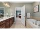 Bathroom with dual vanity, soaking tub, and doorway leading to blue bedroom, offering a serene and luxurious space at 42 Village Walk Dr, Chapel Hill, NC 27517