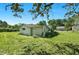 View of a backyard shed with a lush lawn, surrounded by mature trees and clear sky at 441 Cedar St, Henderson, NC 27536