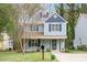 Charming two-story home with light blue siding, black shutters, front porch, and landscaped yard at 4520 Timberhurst Dr, Raleigh, NC 27612