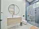 Modern bathroom featuring a floating vanity, round mirror, and a sleek glass-enclosed shower with marble-style tile surround at 4908 Birchleaf Dr, Raleigh, NC 27606
