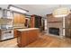 Open kitchen featuring an island, modern appliances, wooden cabinetry, and a brick fireplace at 5125 Penny Rd, Raleigh, NC 27606