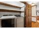 Convenient laundry room featuring modern appliances, storage shelves, and a classic wooden door at 5125 Penny Rd, Raleigh, NC 27606
