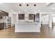 Bright kitchen featuring a large island, stainless appliances, and dark cabinetry with modern lighting at 5420 Mill Dam Rd, Wake Forest, NC 27587