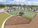 Aerial view of tennis courts and dog park in a new neighborhood with a clubhouse in the distance at 601 Lauren Ann Dr, Apex, NC 27523