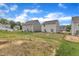 View of backyards with vibrant green grass, houses, and a clear blue sky with fluffy clouds at 717 Little Patch St, Zebulon, NC 27597