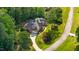 Aerial view features a brick home with manicured landscaping and a long driveway in a wooded lot at 7932 Twin Pines Way, Fuquay Varina, NC 27526