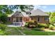Rear exterior featuring brick house with porch, patio, and landscaped garden at 7932 Twin Pines Way, Fuquay Varina, NC 27526