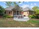 Brick home rear view with large patio, outdoor seating, and professionally landscaped backyard at 7932 Twin Pines Way, Fuquay Varina, NC 27526