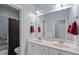 Bright bathroom featuring double sink vanity with a large mirror, red towels, and shower with curtain at 7932 Twin Pines Way, Fuquay Varina, NC 27526