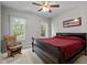 Bedroom featuring a wooden sleigh bed with a red comforter, plush armchair, and natural lighting at 7932 Twin Pines Way, Fuquay Varina, NC 27526