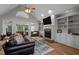 Living room with stone fireplace, hardwood floors, and views of the outdoor porch at 7932 Twin Pines Way, Fuquay Varina, NC 27526