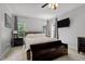 Bright bedroom featuring two windows and hardwood floors, with a decorative bench at the end of the bed at 7932 Twin Pines Way, Fuquay Varina, NC 27526