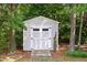 Backyard storage shed with white doors, surrounded by mature trees providing shade and privacy at 7932 Twin Pines Way, Fuquay Varina, NC 27526