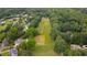Aerial view showcasing a neighborhood surrounded by lush trees and a grassy field at 8042 Hogan Dr, Wake Forest, NC 27587
