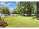 Sprawling backyard with lush green lawn, mature trees, and a playset, creating a serene outdoor space at 816 Trumpet Vine Ct, Wendell, NC 27591