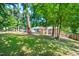 A spacious backyard with mature trees, a well-maintained lawn, and a charming brick house at 903 W Maynard Ave, Durham, NC 27704