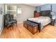 Well-lit bedroom features hardwood floors, a dark wood bedframe and accent chair, and a sunny window at 903 W Maynard Ave, Durham, NC 27704