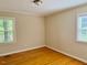 A bright bedroom with hardwood floors, two windows, and neutral colored walls at 1005 Driftwood Dr, Siler City, NC 27344