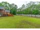 View of a large backyard with a wood fence, lush lawn, and a storage shed, offering ample space at 1016 Luminary Ln, Willow Springs, NC 27592