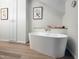Spa-like bathroom with a freestanding tub, wood-look flooring, and soft natural light at 107 Long Shadow Ln, Cary, NC 27518