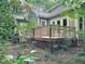 Back of home with wooden deck and stairs surrounded by mature trees and landscaping at 107 Long Shadow Ln, Cary, NC 27518