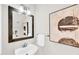 Stylish half bathroom with a sleek vanity, mirror, modern light fixture, and elegant abstract artwork at 110 Glenrose Ln, Cary, NC 27518