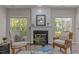 Cozy living room featuring a fireplace, hardwood floors, and natural light from two large windows at 110 Huntersville Rd, Morrisville, NC 27560