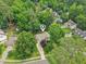 An aerial view shows a home nestled among lush trees in a serene neighborhood with a long driveway at 1102 Laurens Way, Knightdale, NC 27545