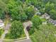 An aerial view shows a home nestled among lush trees in a serene neighborhood with a long driveway at 1102 Laurens Way, Knightdale, NC 27545
