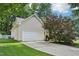 Side view of a two-car garage with white door and neutral siding, nestled in a well-kept yard at 1102 Laurens Way, Knightdale, NC 27545