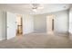 Spacious carpeted bedroom with neutral walls, ceiling fan, and open doorways to hall and closet at 111 Laporte Path, Garner, NC 27529