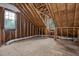 Unfinished attic features wooden beams, plywood floor, and window, offering renovation potential at 1113 Smokewood Dr, Apex, NC 27502