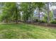 Fenced backyard showing green lawn and mature trees, providing a secluded outdoor area at 1113 Smokewood Dr, Apex, NC 27502