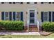 Home entrance features a glass door, flanked by sidelights, with navy shutters, and manicured shrubs at 1113 Smokewood Dr, Apex, NC 27502