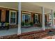 Inviting front porch area with brick steps, white columns, rocking chairs, and fresh potted plants at 114 Fieldstone Dr, Burlington, NC 27215