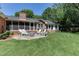 Brick home's backyard with stone patio featuring a fire pit and white Adirondack chairs at 1206 Ivy Ln, Raleigh, NC 27609