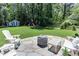 Expansive backyard with stone patio, fire pit, Adirondack chairs and a swing set at 1206 Ivy Ln, Raleigh, NC 27609