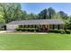 Charming brick home featuring lush green lawn, manicured hedges and a bright red front door at 1206 Ivy Ln, Raleigh, NC 27609