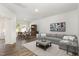 Bright living room with sleek hardwood floors, grey sofa, and natural light from the window at 1230 Adrian Ct, Mebane, NC 27302