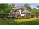 Back exterior view of home with well-manicured landscaping, lush green lawn, mature trees, and covered porch at 1329 Wynncrest Ct, Raleigh, NC 27603