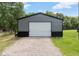 View of a detached metal garage with a gravel driveway and green grass at 165 Dawn Rd, Benson, NC 27504
