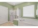 Bright bathroom featuring a soaking tub, glass shower, and neutral tile flooring at 204 Dowington Ln, Cary, NC 27519