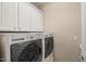 Well-equipped laundry room with modern washer, dryer, and overhead cabinets at 204 Dowington Ln, Cary, NC 27519