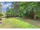 Lush backyard with green grass, mature trees, privacy fence, and outdoor seating at 209 Woodstar Dr, Cary, NC 27513