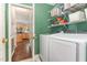 Green laundry room with white washer and dryer, plus convenient wall shelves and view of the kitchen at 209 Woodstar Dr, Cary, NC 27513