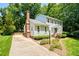 Traditional two-story home with a brick chimney, landscaping, driveway, and a welcoming front porch at 2107 Somers Ave, Burlington, NC 27215