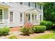 Close-up of front entrance with a covered porch, flowers, verdant shrubs, and stone walkway at 2107 Somers Ave, Burlington, NC 27215