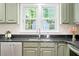 A kitchen sink sits in front of a window, stainless steel appliances, with olive green cabinets at 2107 Somers Ave, Burlington, NC 27215